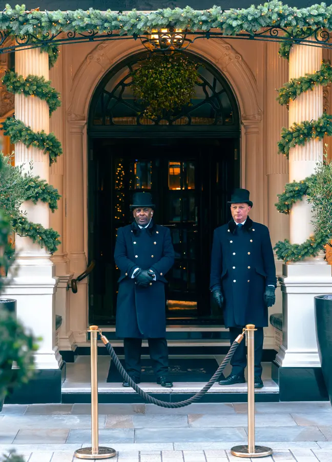 A concierge in tailored hotel uniform at the entrance of a property