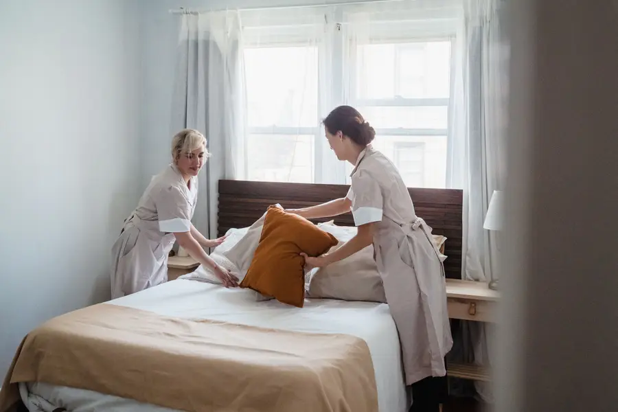 A housekeeper in uniform making up a room